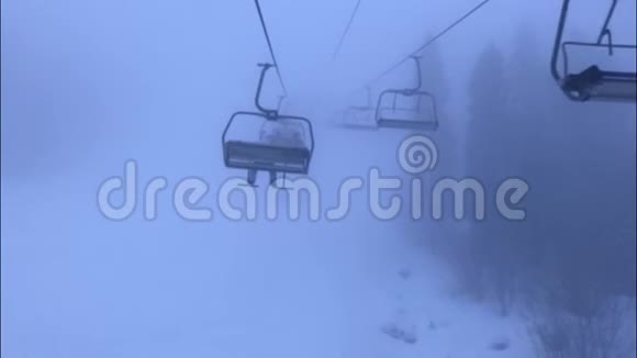 高山滑雪椅在雾中升起山区多云的雪天视频的预览图