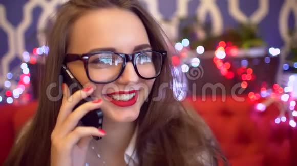 漂亮的戴眼镜的女人在咖啡馆里用手机说话4k智能手机的女人在咖啡馆里坐着打电话视频的预览图