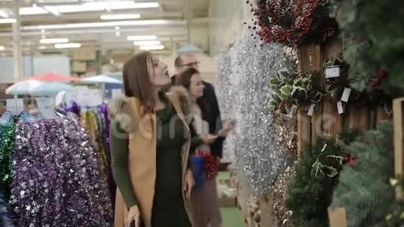 在超市里挑选圣诞花圈的一群朋友视频的预览图