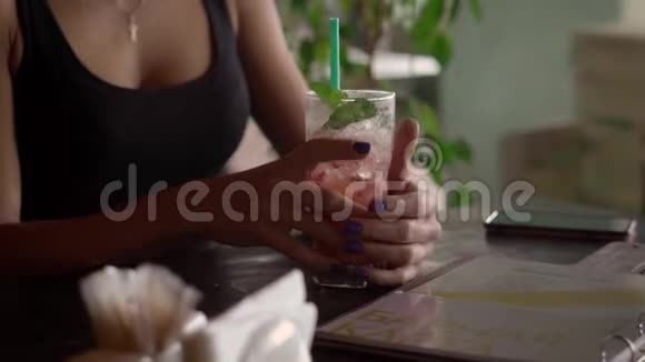 一位年轻貌美的女士拿着一杯装满冰的鸡尾酒视频的预览图
