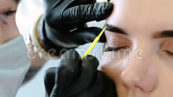 美容师用棉签擦拭女人眉毛修正眉毛特写前景视频的预览图