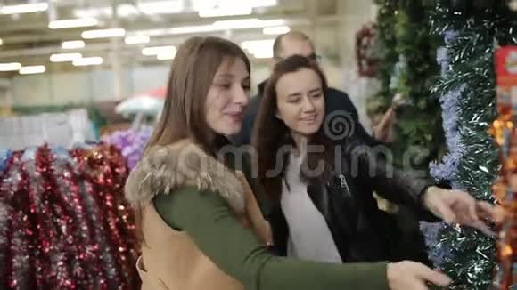 快乐的朋友在圣诞节前在超市买东西带着圣诞花环的背包视频的预览图