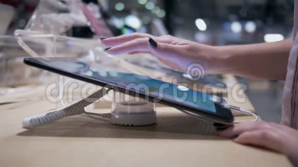 买家测试小工具女孩在电子商店购物时使用带触摸屏的现代平板电脑视频的预览图