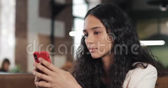 商务女性在咖啡馆使用智能手机应用程序在手机上发短信粉色的漂亮休闲女专业视频的预览图