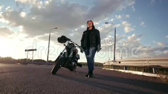 一个穿着皮夹克戴着手套的老太婆骑着摩托车站在他旁边直着头那个女人把她折叠起来视频的预览图