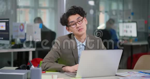 亚洲商人在舒适的办公室里的笔记本电脑工作视频的预览图