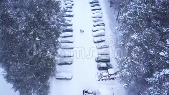 森林冬季停车场俯视图削减年在森林里有人在路中间行走的雪地停车场视频的预览图