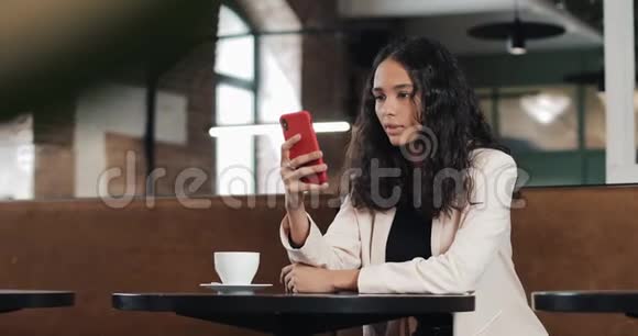 商务女性在咖啡馆使用智能手机应用程序在手机上发短信粉色的漂亮休闲女专业视频的预览图