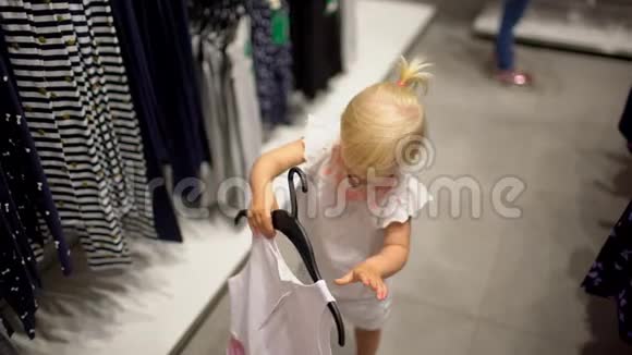 小女孩在超市里挑选衣服快乐的一家人在购物在商场里的家人视频的预览图