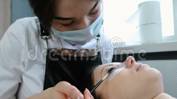 美容治疗美容师在睫毛上涂上黑色油漆肉毒杆菌和复膜睫毛视频的预览图