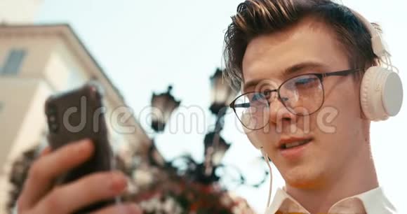 上面画着一个戴着眼镜的帅哥他用智能手机聊天通过音乐听音乐视频的预览图