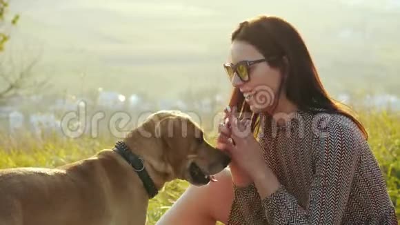 戴太阳镜的漂亮女孩轻轻抚摸她可爱的狗视频的预览图