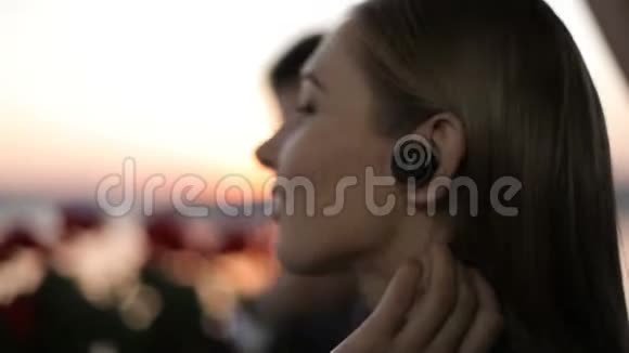 美丽的女士带着无线耳机在湖边的户外咖啡馆放松特写视频的预览图