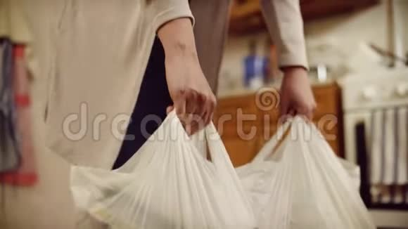 女人把包裹放在地板上女人的特写双手放在地上沉重的食物袋里家庭食品采购视频的预览图