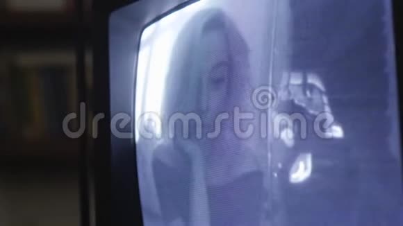 金发女孩模糊地看着镜头出现在复古电视机的屏幕上视频的预览图