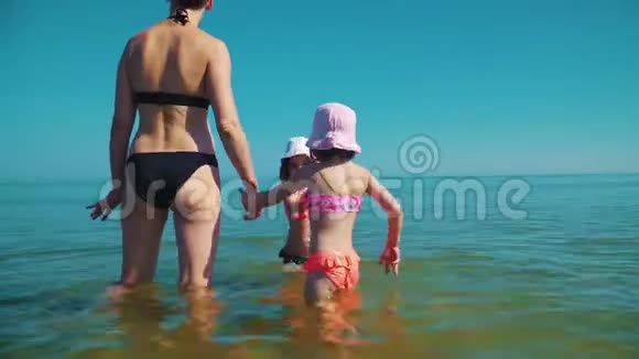 妈妈和两个可爱的女儿站在海里视频的预览图