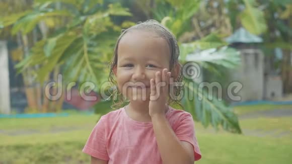 一幅5岁的女孩在热带雨中看镜头的肖像视频的预览图