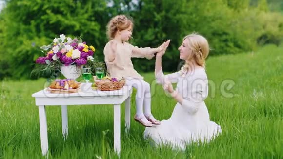 一个穿着漂亮衣服的小女孩坐在桌子上高兴地和妈妈在手里玩圣帕特里克节视频的预览图