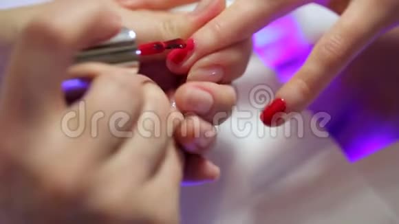 美容师把红色指甲油涂在年轻女性的指甲上指甲护理视频的预览图