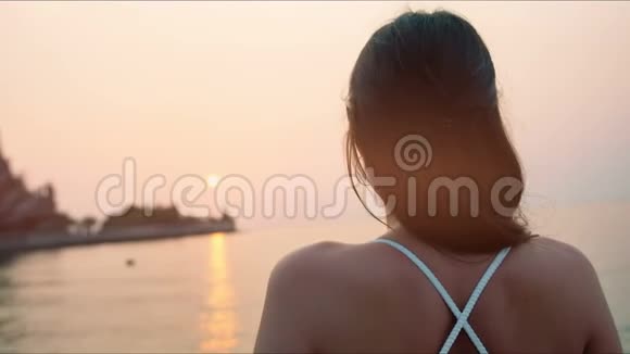 日出时观看海上美景的年轻女子视频的预览图