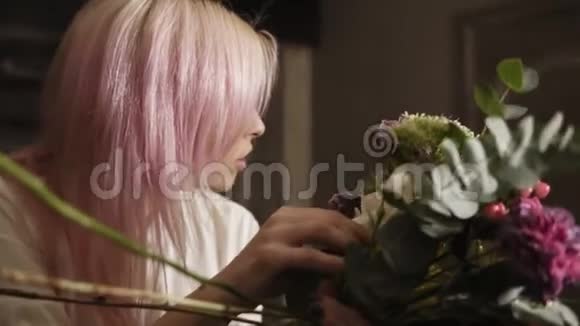 一个美丽的花匠女孩纠正并填满了一束花花在镜子里看着它视频的预览图