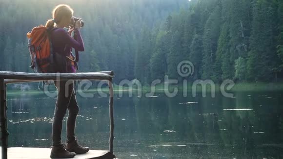 带背包的年轻女孩徒步旅行者在森林湖拍照视频的预览图