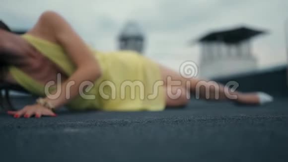 一个穿着黄色衣服的女孩正在屋顶上摆姿势在背景蓝天和屋顶的房子视频的预览图