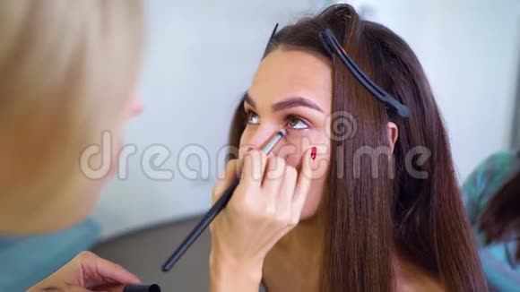在美容院为年轻的黑发女人化妆的化妆师视频的预览图