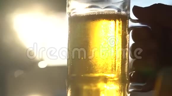 近距离用手拿着带阳光的啤酒杯视频的预览图