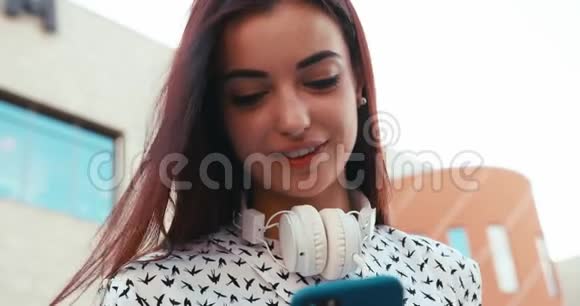 迷人的黑发女士带着美丽的微笑在户外的手机上聊天上面的肖像4K录像视频的预览图