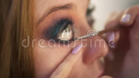 年轻女模特的特写镜头正在演播室上演艺术家正在将黑色衬垫涂在右眼的下盖上视频的预览图