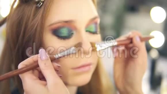 化妆师用粉底和两把刷子给这个年轻女人做鼻子的结构眼睛补完了关门视频的预览图