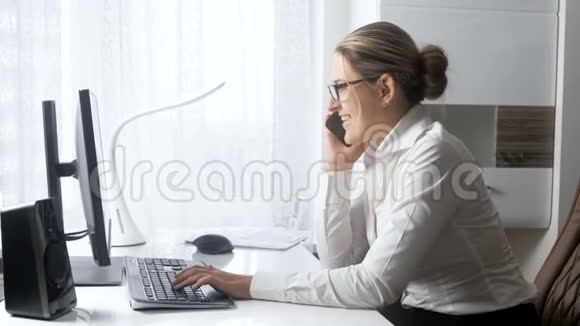 在办公室里微笑的女商人通过电话交谈和浏览社交媒体网站视频的预览图