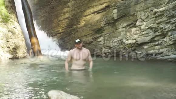 游客在岩石山上的湖里洗澡徒步旅行很长一段时间后使自己精神焕发视频的预览图