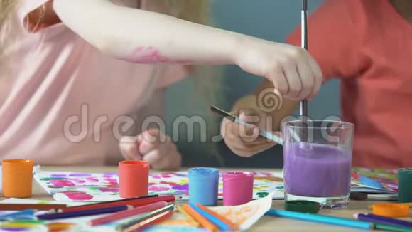 在儿童艺术俱乐部上绘画课孩子们把画笔放进水杯里视频的预览图