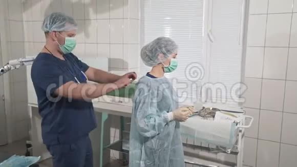 一组戴口罩的医生正在为手术做准备助手帮助外科医生进行无菌手术视频的预览图