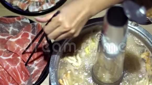 牛肉生肉拿筷子火锅与甜甜圈形状的黄铜锅视频的预览图