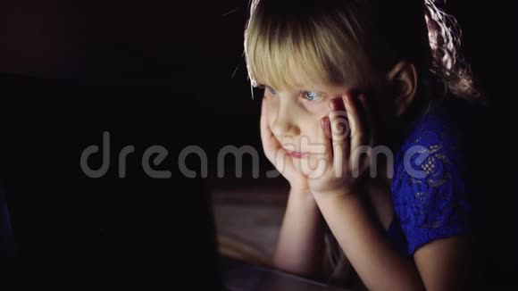 小女孩在笔记本电脑上看起来很卡通发光的笔记本电脑屏幕照亮孩子脸视频的预览图