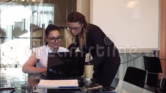 两个女商人用一台心情好的电脑在办公室讨论一个商业项目视频的预览图
