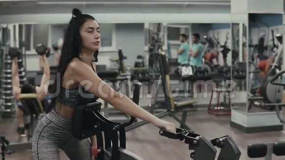 穿灰色运动服的健身女孩在健身器里做运动视频的预览图