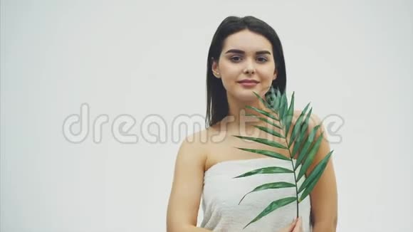 美丽的年轻女性完美的皮肤和自然的构成摆在植物热带绿叶的前面背景是视频的预览图