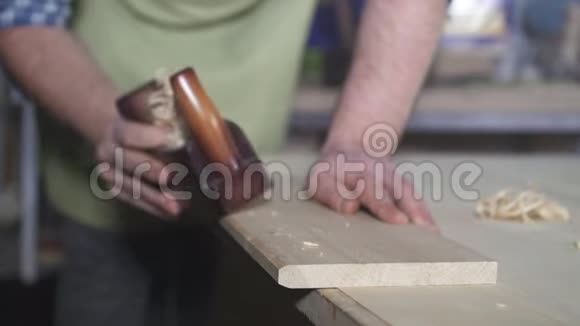 用一个旧的手工工具刨削和飞木刨削把一个男木匠围起来视频的预览图