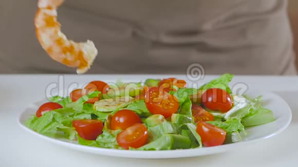 厨房里的一个男人准备了一份牛油果西葫芦和樱桃西红柿的沙拉并把大的开胃虾放在上面视频的预览图