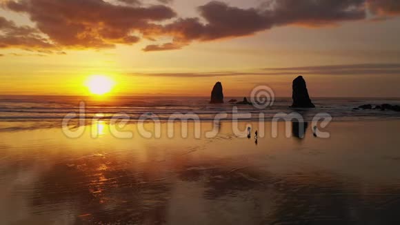 人们漫步坎农海滩太平洋波浪反射日落的光辉视频的预览图