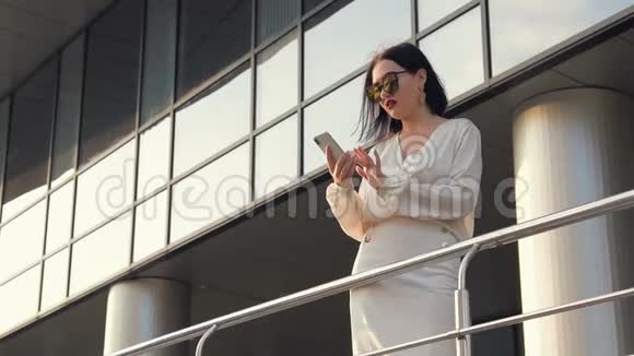 年轻漂亮的女商人穿着白色衬衫和黑色西装沿着扶手沿着街走靠在栏杆上视频的预览图
