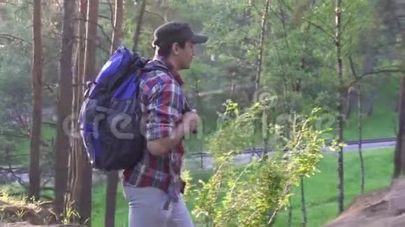 穿着格子衬衫的人带着一个大背包在公园里散步视频的预览图