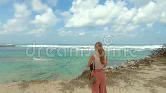 印度尼西亚巴厘岛上一位带着巨浪的美拉斯蒂海滩的年轻女子在海滩上击中视频的预览图