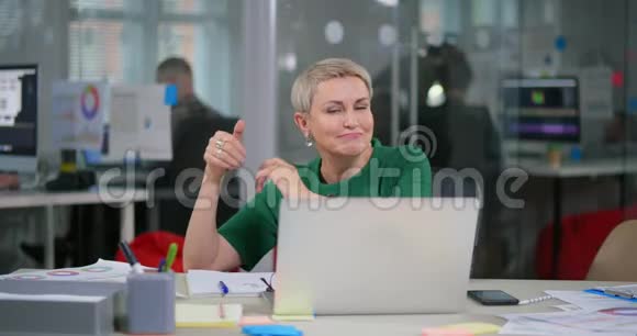白种人成熟的女人坐在笔记本电脑前跳舞视频的预览图