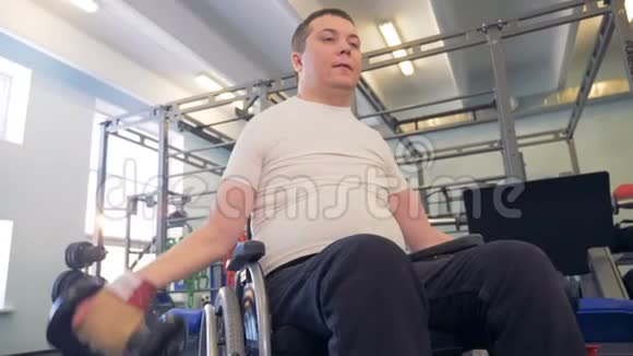坐轮椅的残疾运动员通过哑铃来增强双手的力量视频的预览图