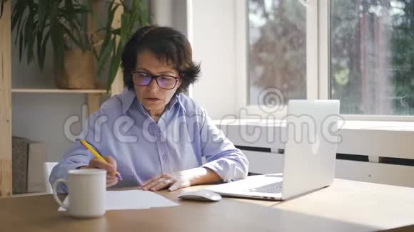 成熟的女商人正拿着笔记本电脑在家里办公视频的预览图